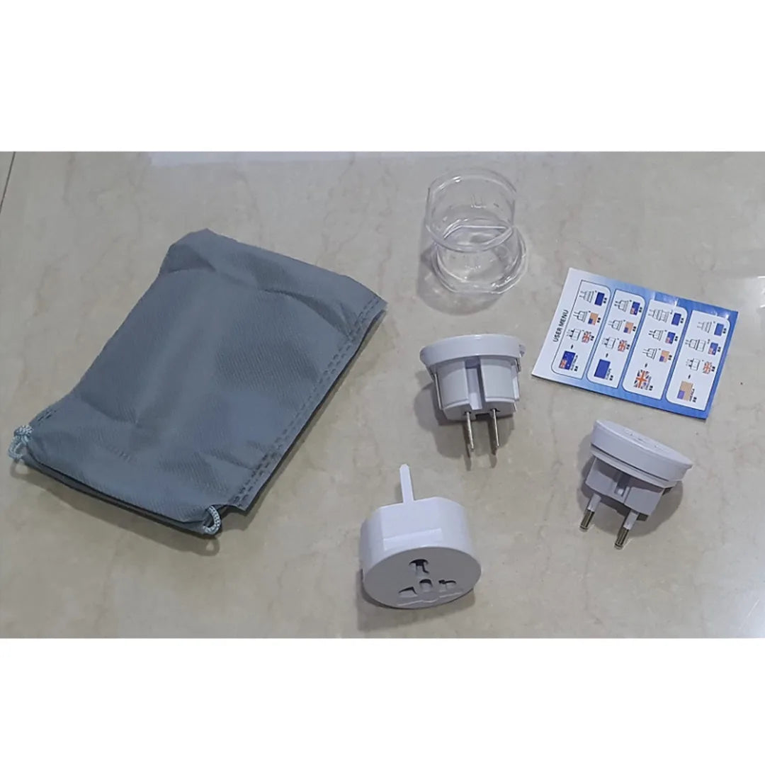 Set of travel adapters, a clear plastic cup, and a gray pouch on a beige surface.