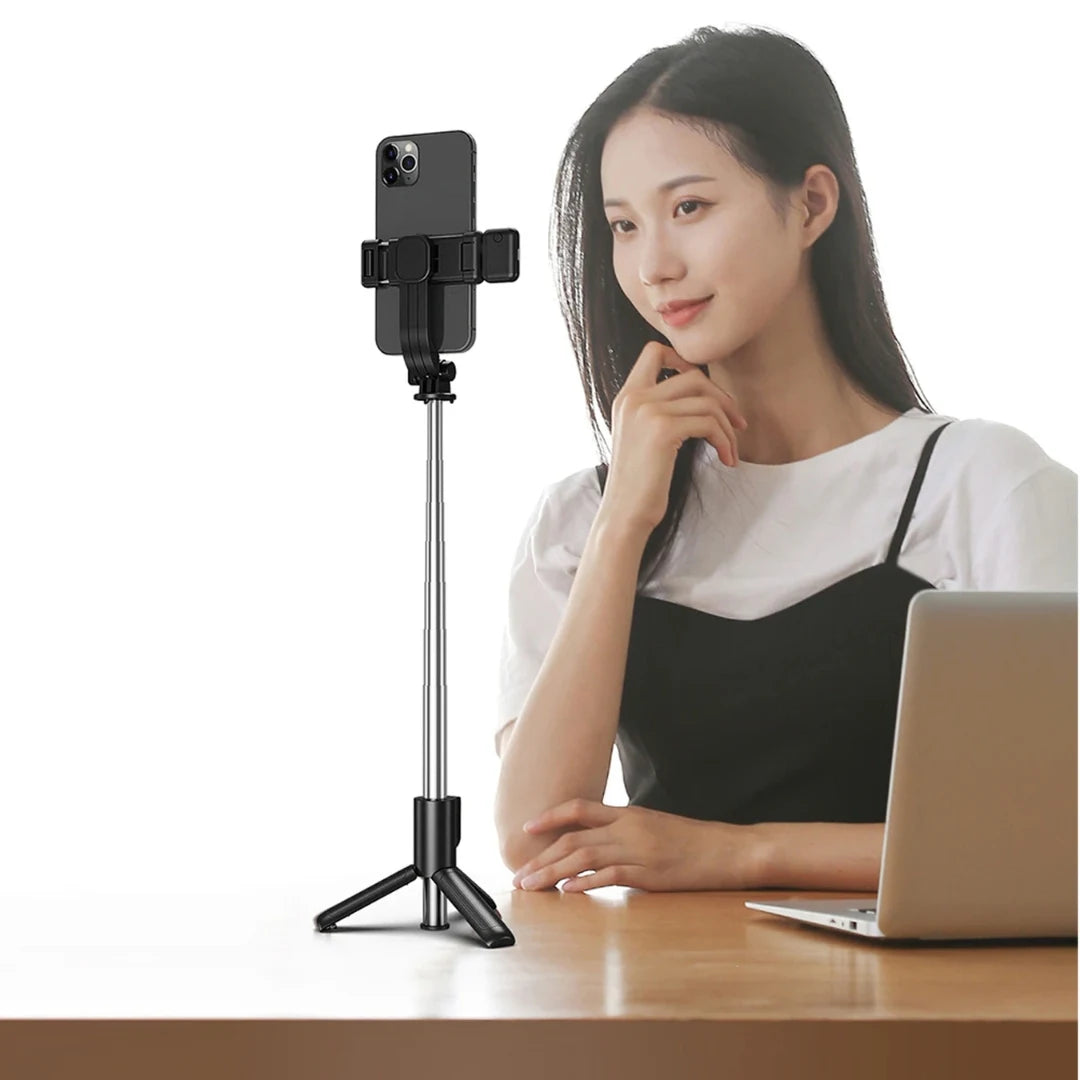 Woman sitting at a desk with a smartphone on a stand and a laptop.