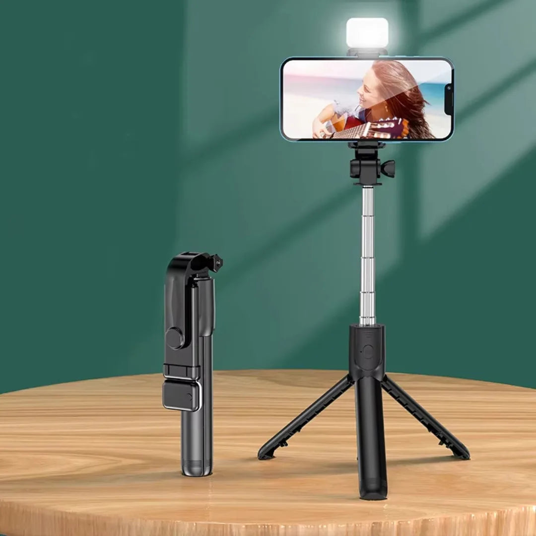 Smartphone with a selfie stick and light on a wooden surface against a green background