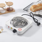 Single burner electric stove on a white surface with bread and a cooling rack in the background.