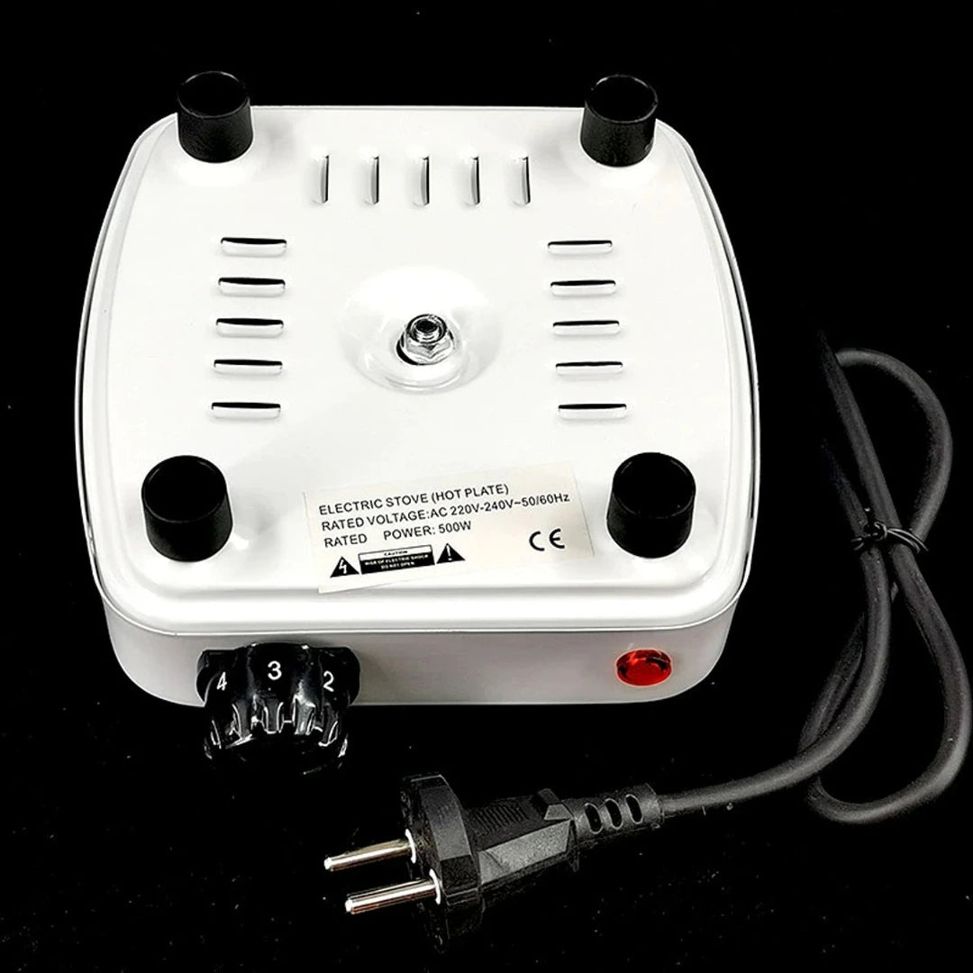 White electric stove hot plate with black knobs and power cord on a black background