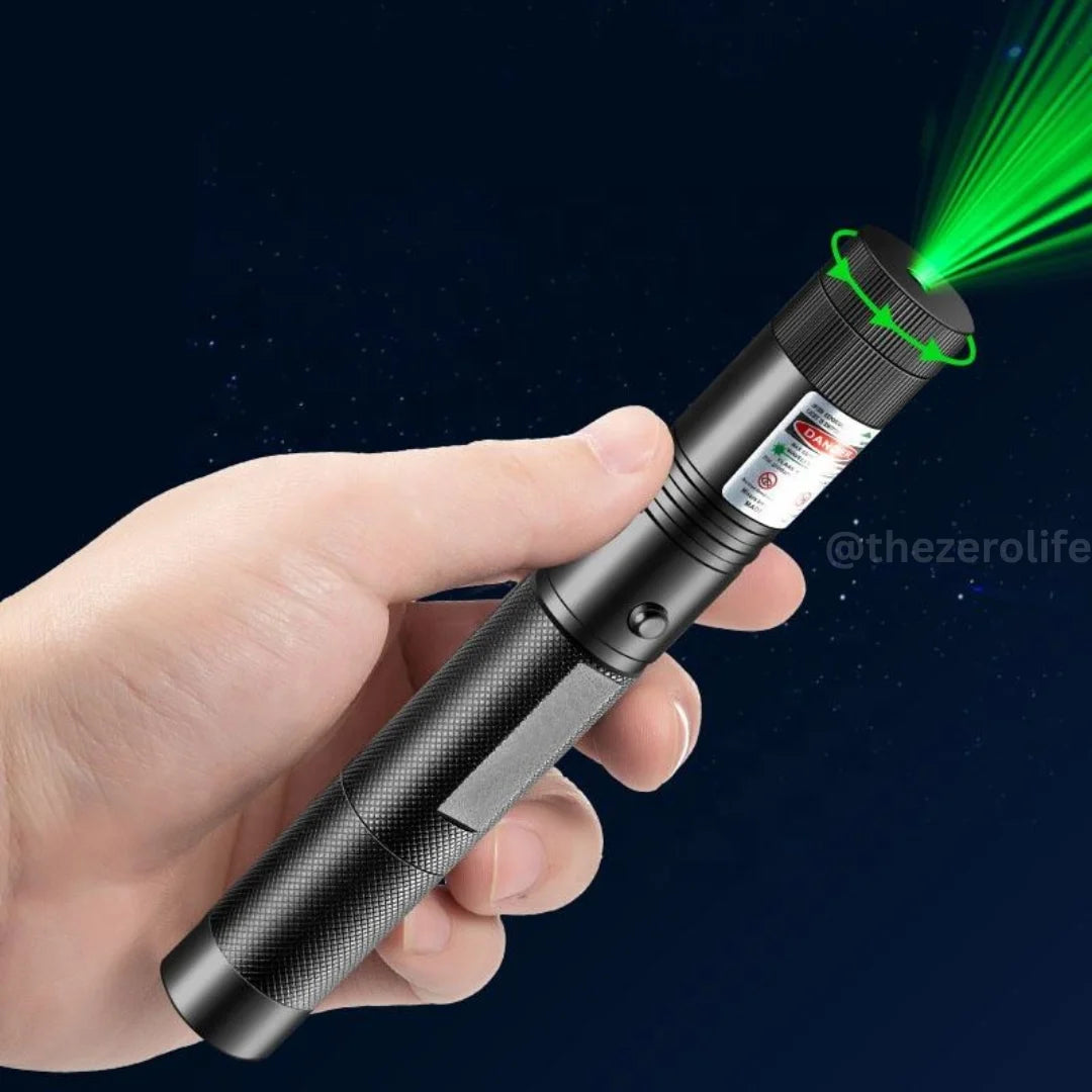 Hand holding a laser pointer with green light on a dark background