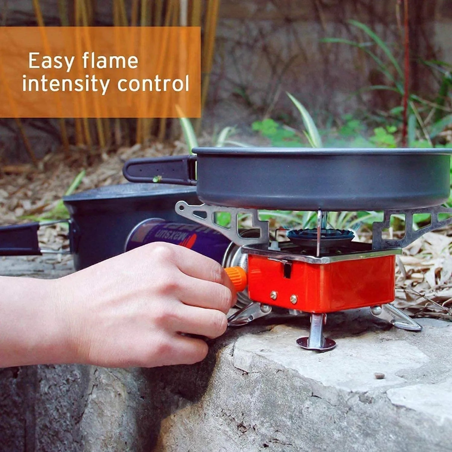 Hand adjusting a camping stove with a pan on a natural background