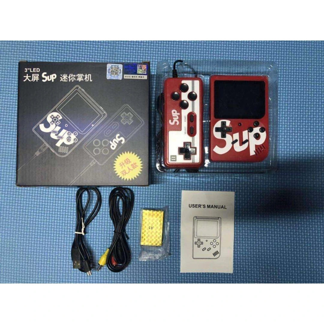 Handheld gaming console with packaging, cable, and user manual on a blue mat